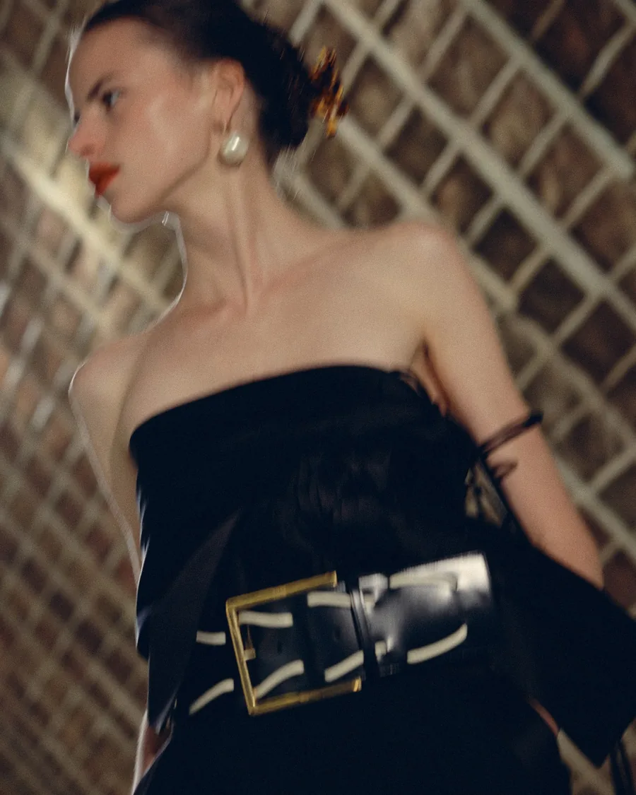 Celine Spring-Summer 2027 close up: strapless black top, wide black belt with a gold buckle and a pearl earring