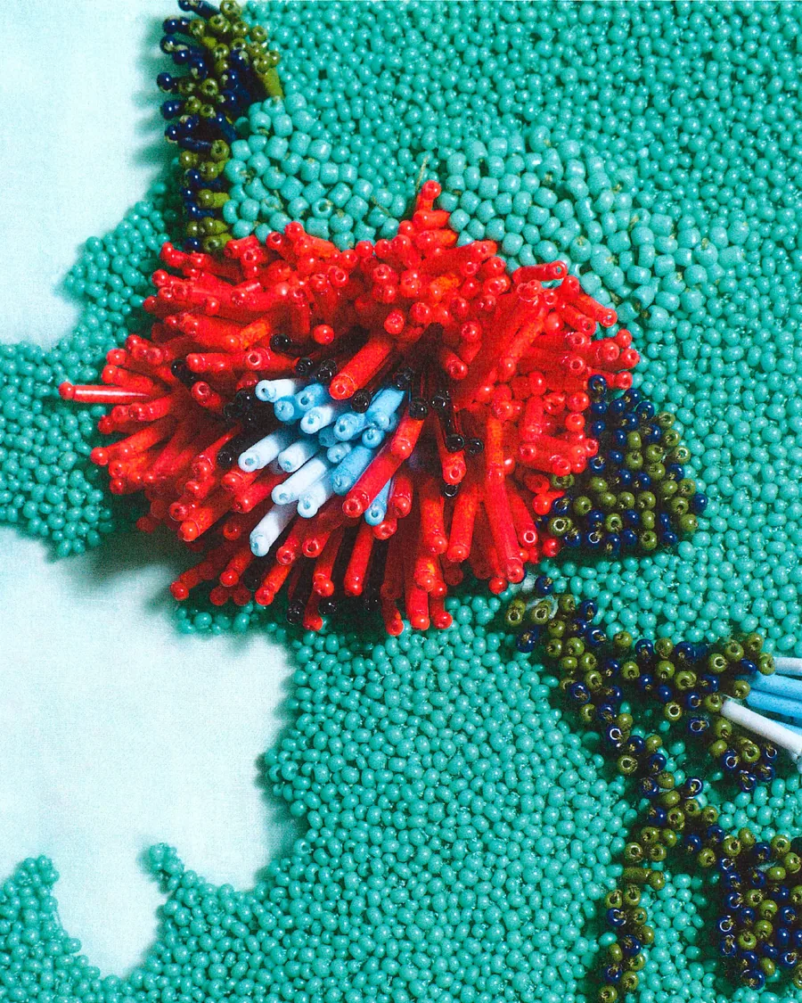 Loewe Spring-Summer 2027 making of: a red flower embroidered in glass beads on a turquoise ground