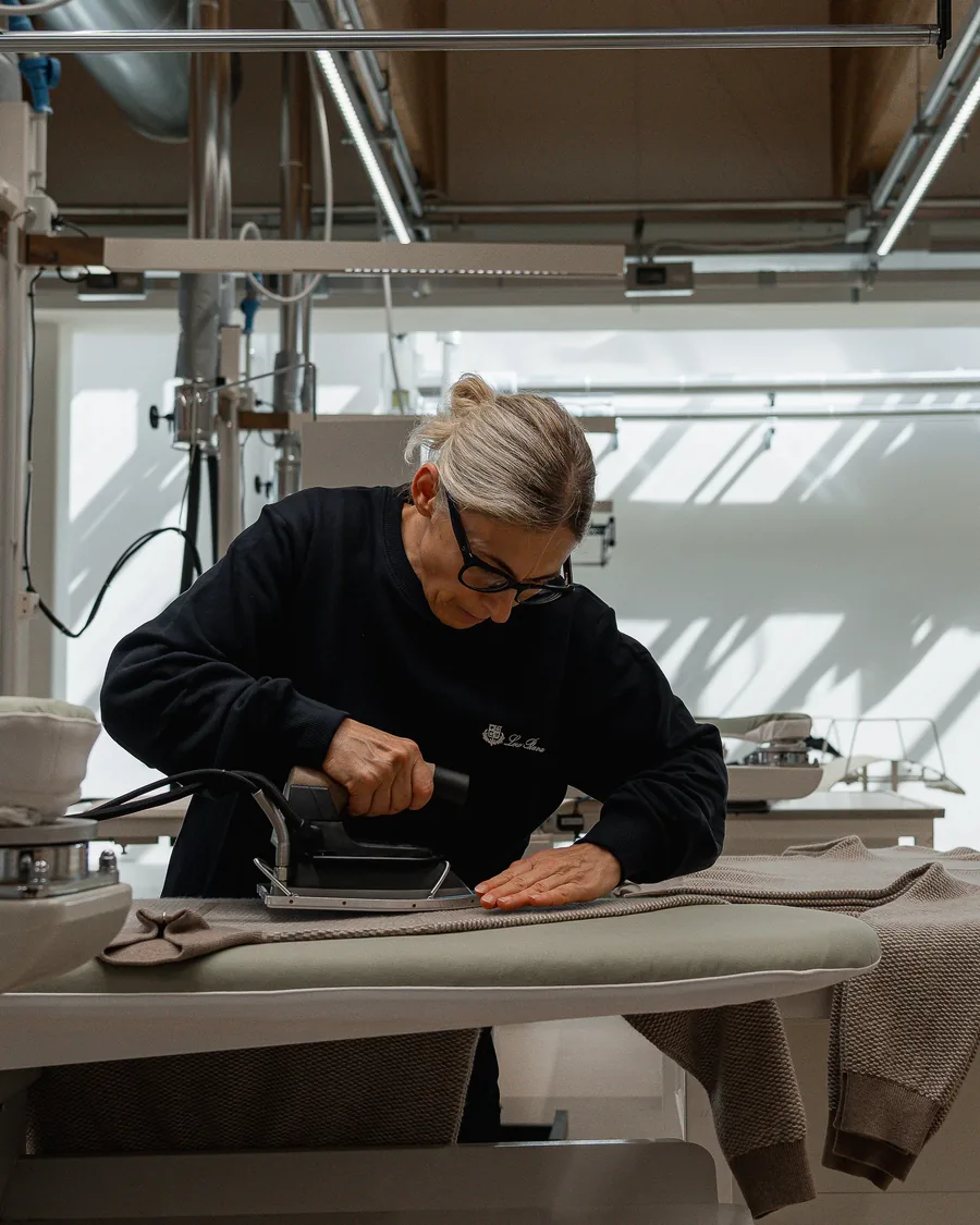 Loro Piana artisan pressing a knitted piece at the finishing table in Ghemme